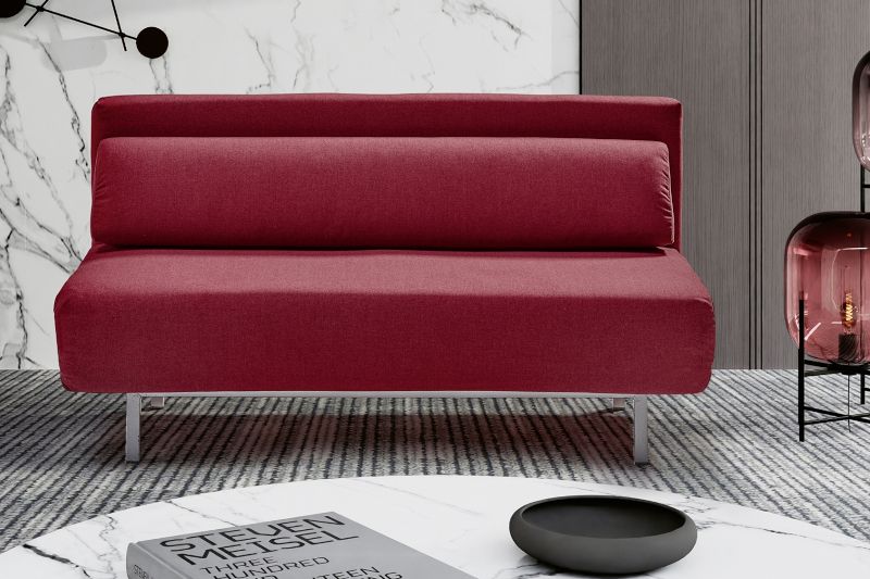Imagen recortada de salón con un sofá cama tapizado en textil de color burdeos.
